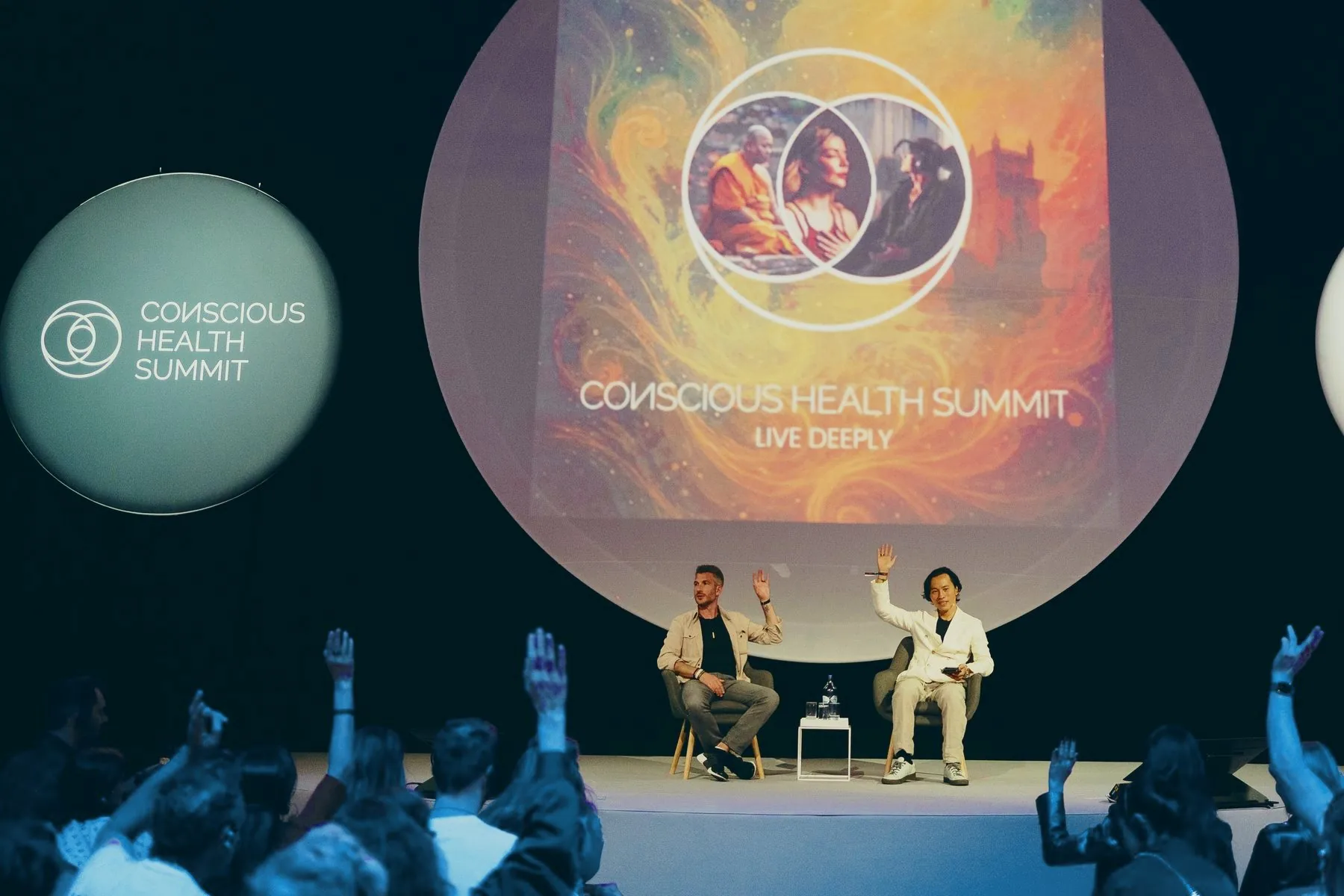 Two hosts and the audience under the big screens of the Science Stage, 2025